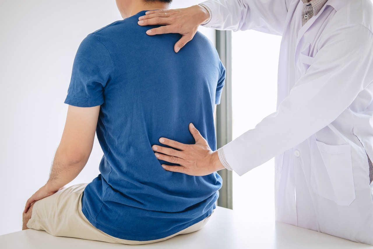 Doctor physiotherapist treating lower back pain patient after wh