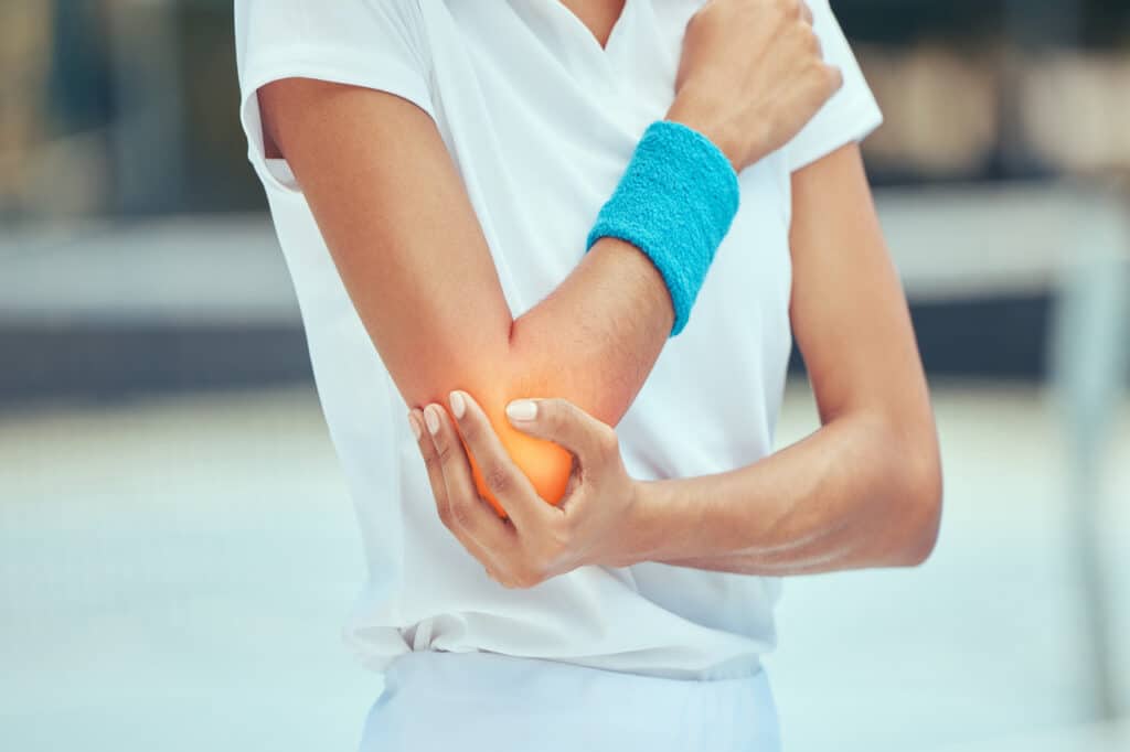 Tennis elbow, pain and injury with a sports woman holding her joint during training, workout and exercise. Fitness, health and accident with a female athlete in a game or match on a court outside